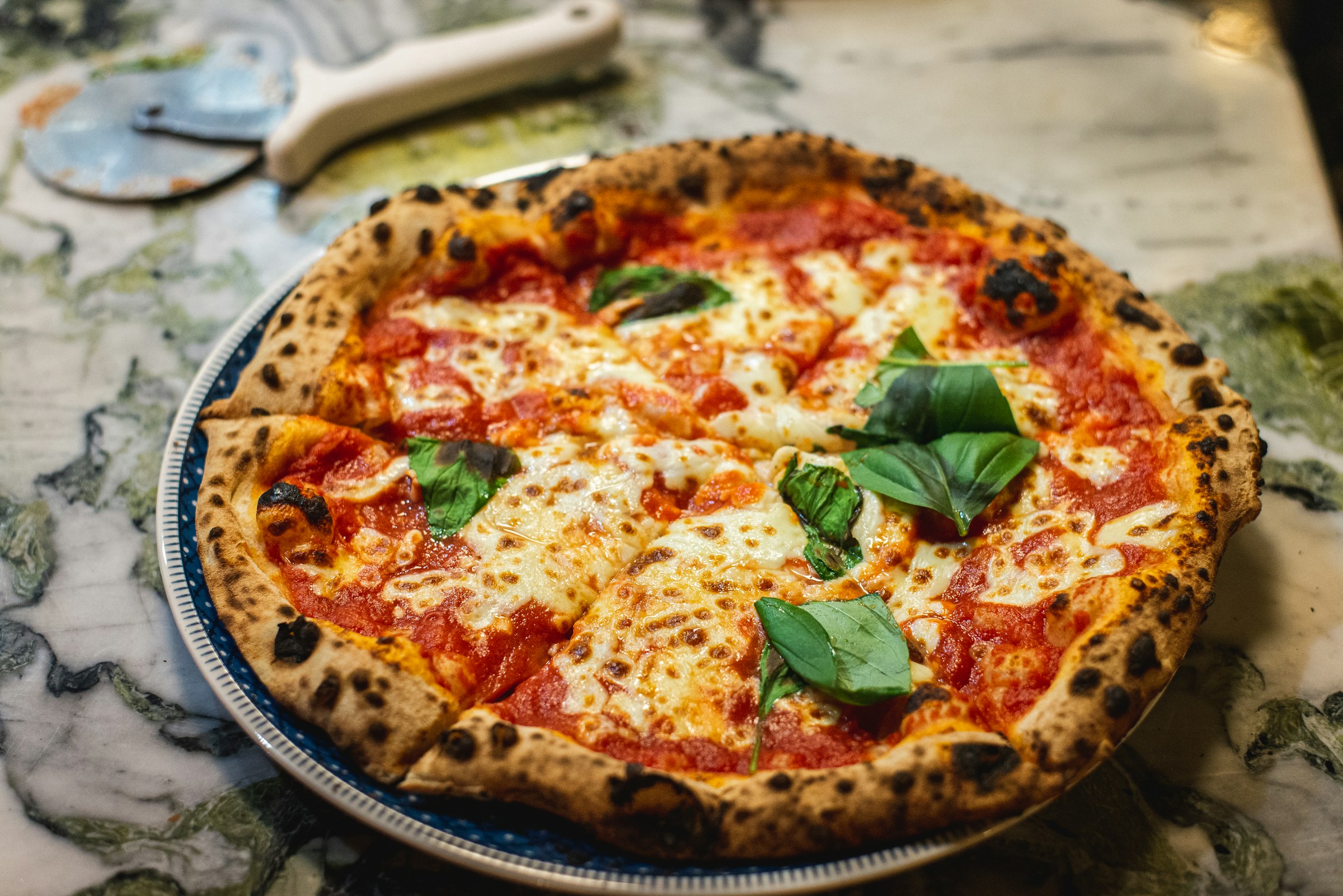 Pizza napoletana margherita con cornicione cotto a legna su marmo scuro